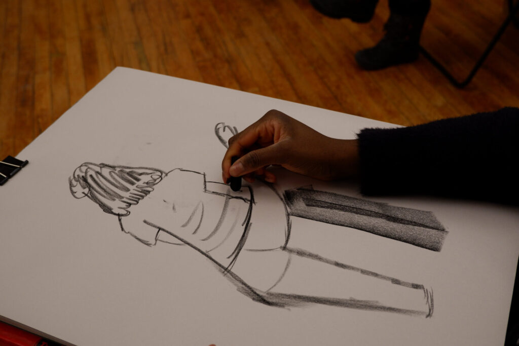 Hand creating a charcoal silhouette on a large format.
