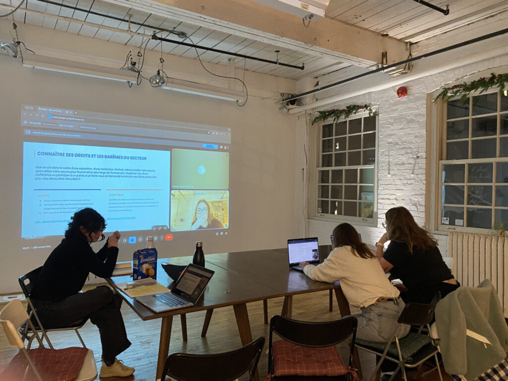 Participantes réunies autour d'une table lors d'un atelier professionnel avec présentation projetée au mur