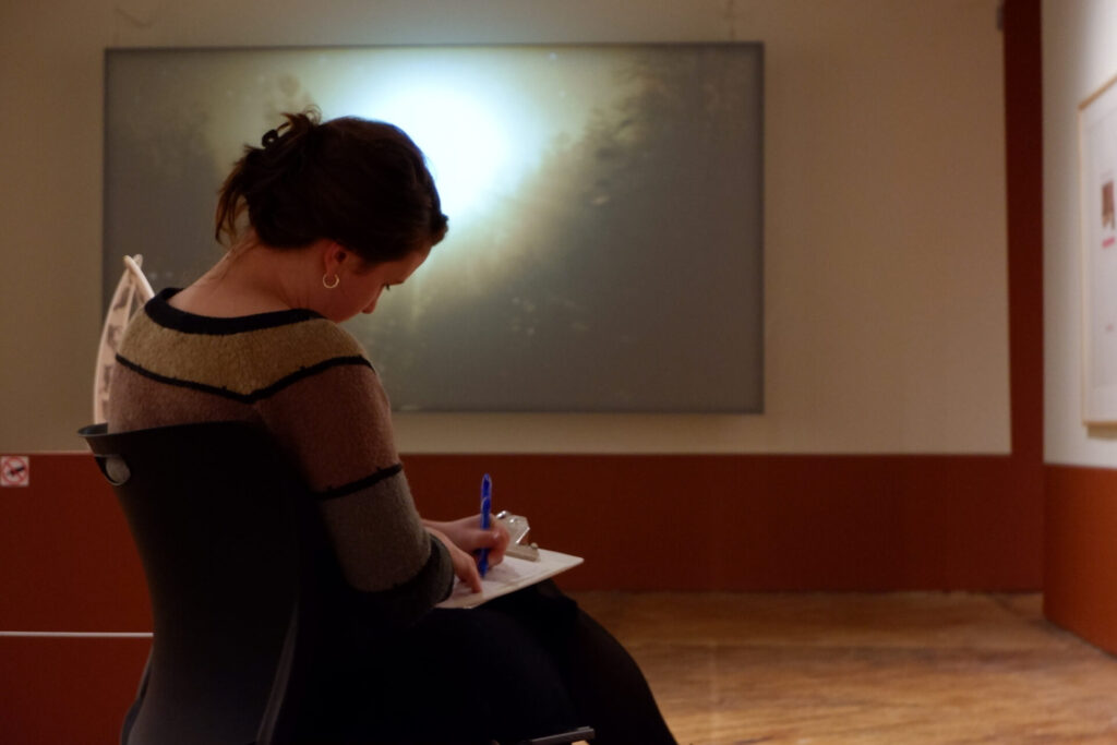 A participant writing in front of an artwork during the gallery workshop.