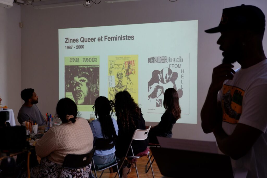 Participant.e.s assistant à une présentation sur les zines dans l'atelier de création artistique.