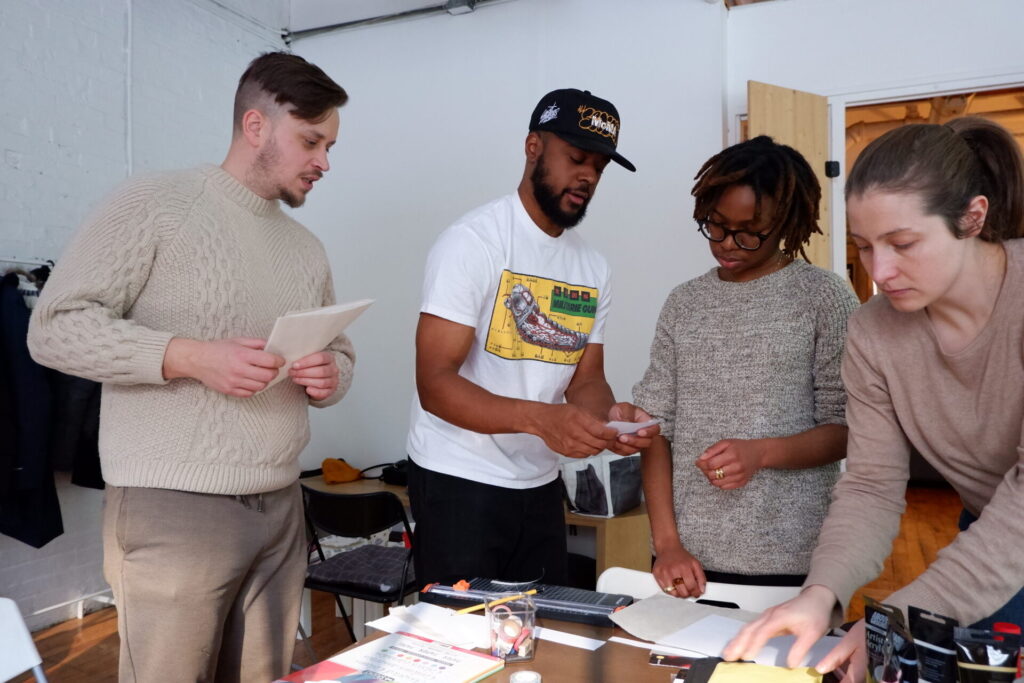Participant.e.s échangeant et manipulant des supports papier lors de l'atelier de création de zine.