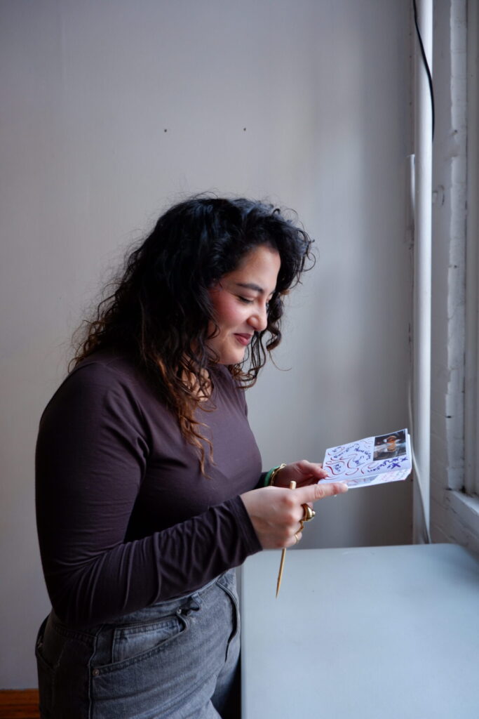 Une participante regardant un zine illustré près d'une fenêtre lors de l'atelier de création de zine.
