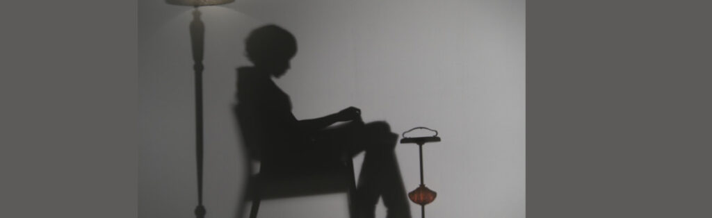 Silhouette d’une femme assise dans une pièce sombre, éclairée latéralement, évoquant une scène contemplative du film Johanne tout simplement.