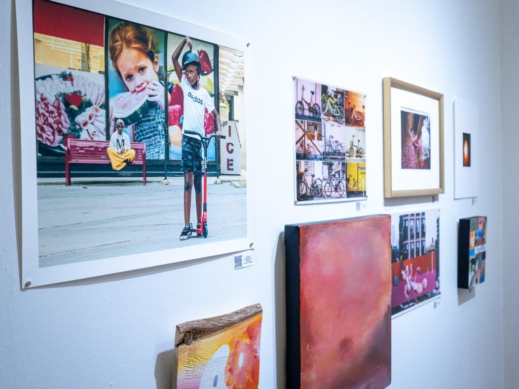 Vue d’un mur d’exposition présentant une variété d’œuvres encadrées et de formats artistiques divers.