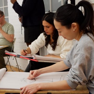 Deux participantes concentrées dessinent sur de grandes feuilles fixées à des planches à dessin pendant l'atelier.